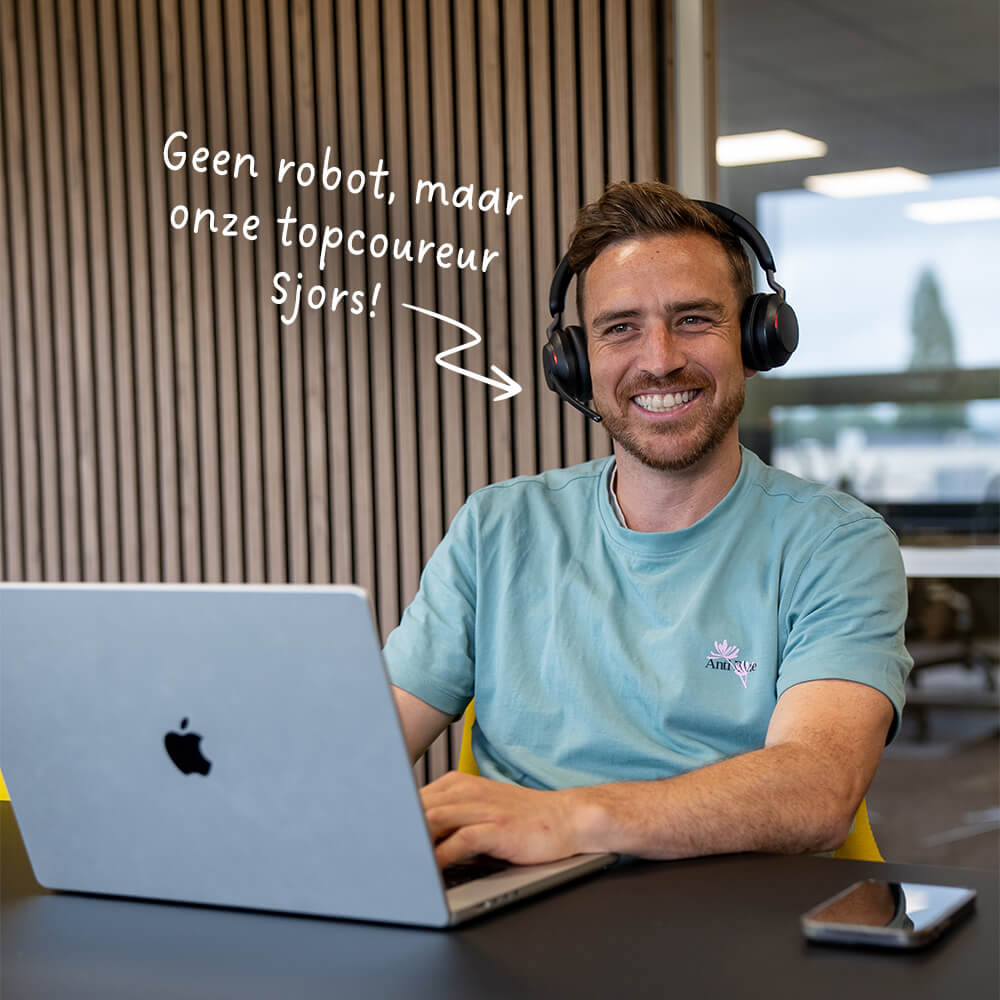 Lachende man met headset werkt op laptop in kantoor met tekst onze topcoureur Sjors