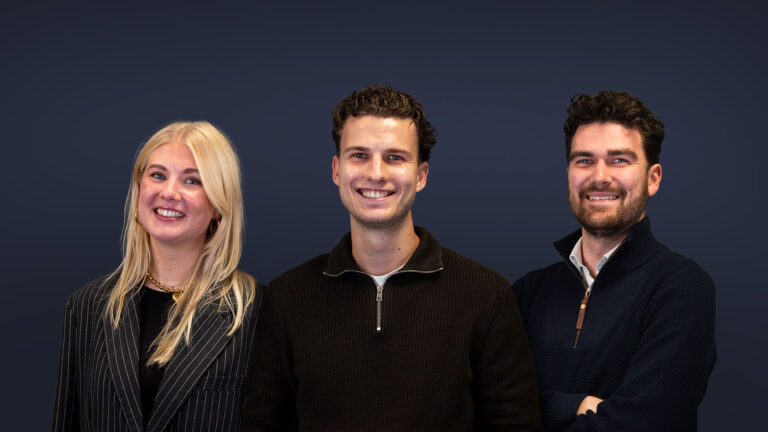 Drie lachende teamleden van Left Lane voor een donkere achtergrond