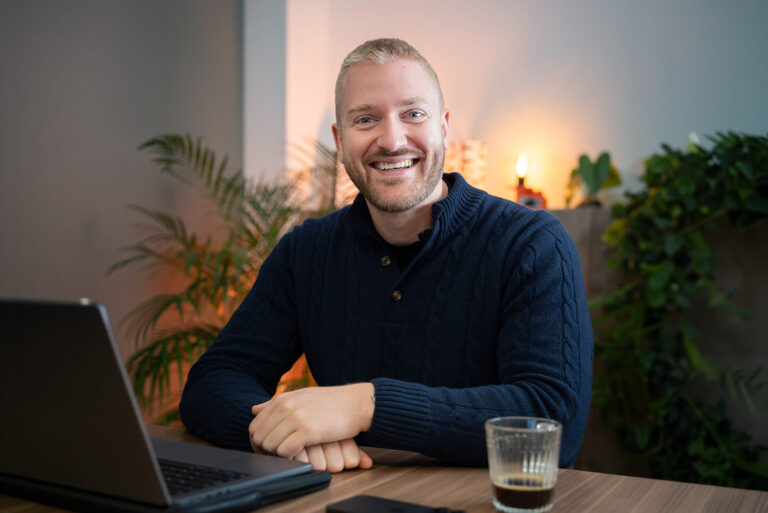 Jerom, eigenaar en employer branding specialist bij Left Lane, lacht aan zijn bureau met laptop